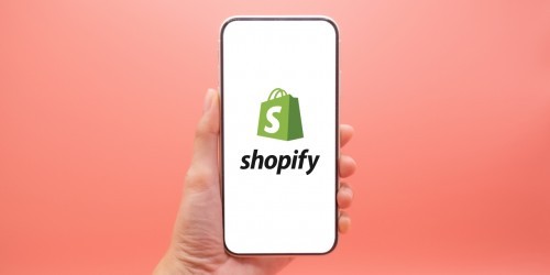 hand holding a phone with the shopify logo